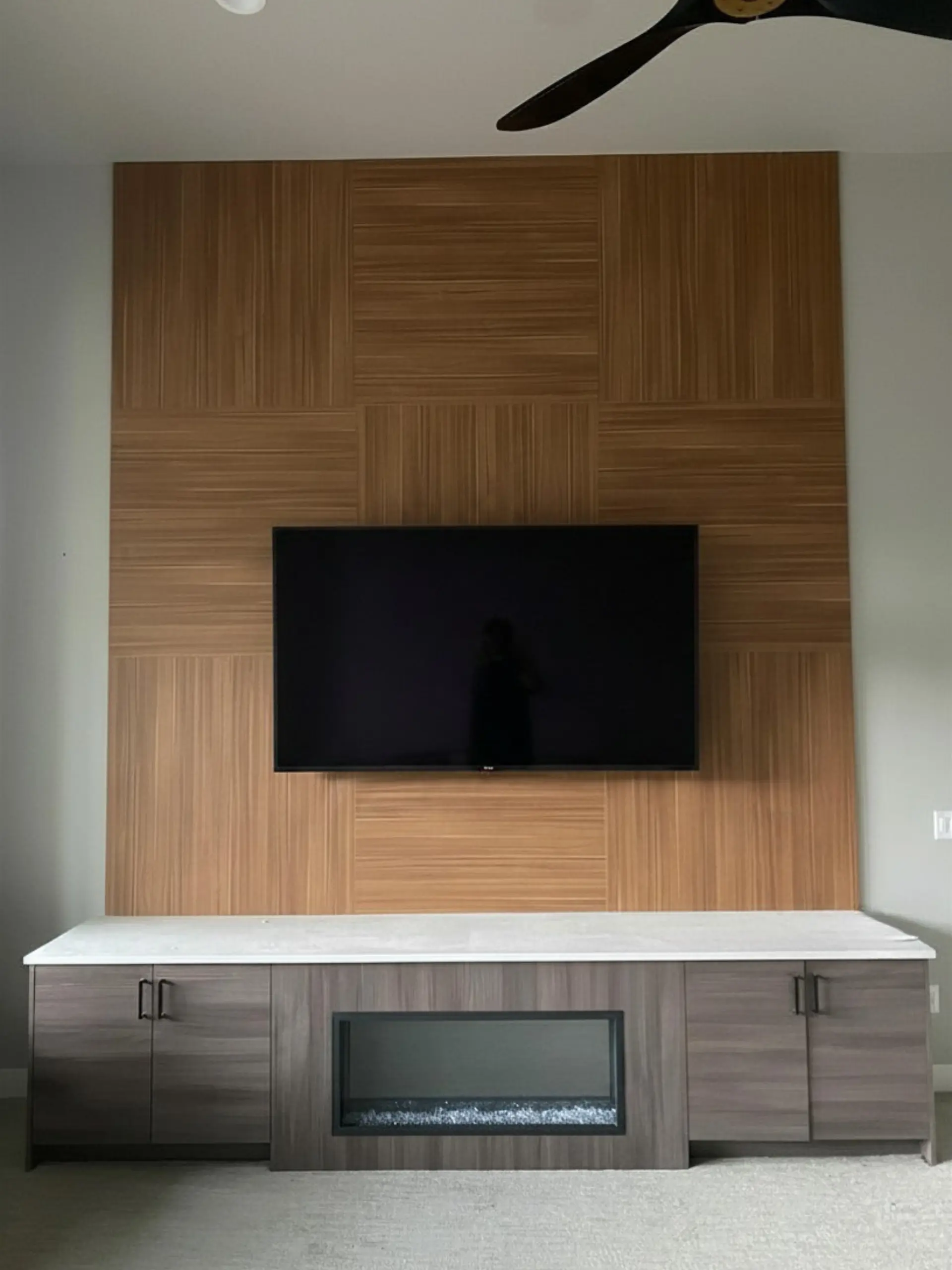 Custom wood veneer panel accent wall with integrated entertainment center and fireplace