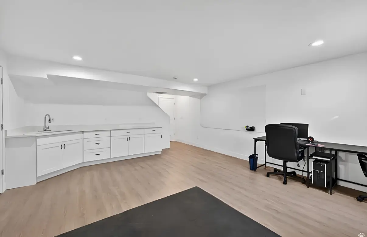 Finished basement featuring custom white cabinetry, wet bar with sink, and LVP flooring