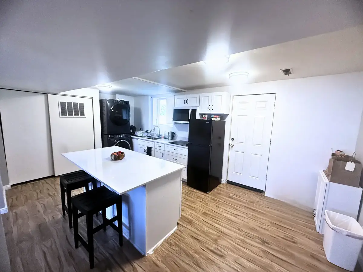Clean, functional basement kitchenette with white shaker cabinets, quartz island, and LVP flooring