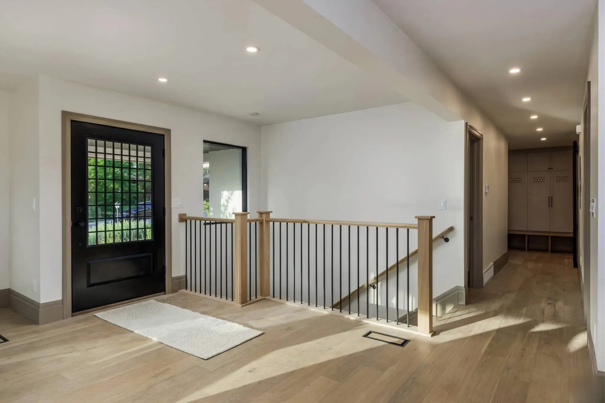 Full staircase railing upgrade with natural wood treads and black iron spindles