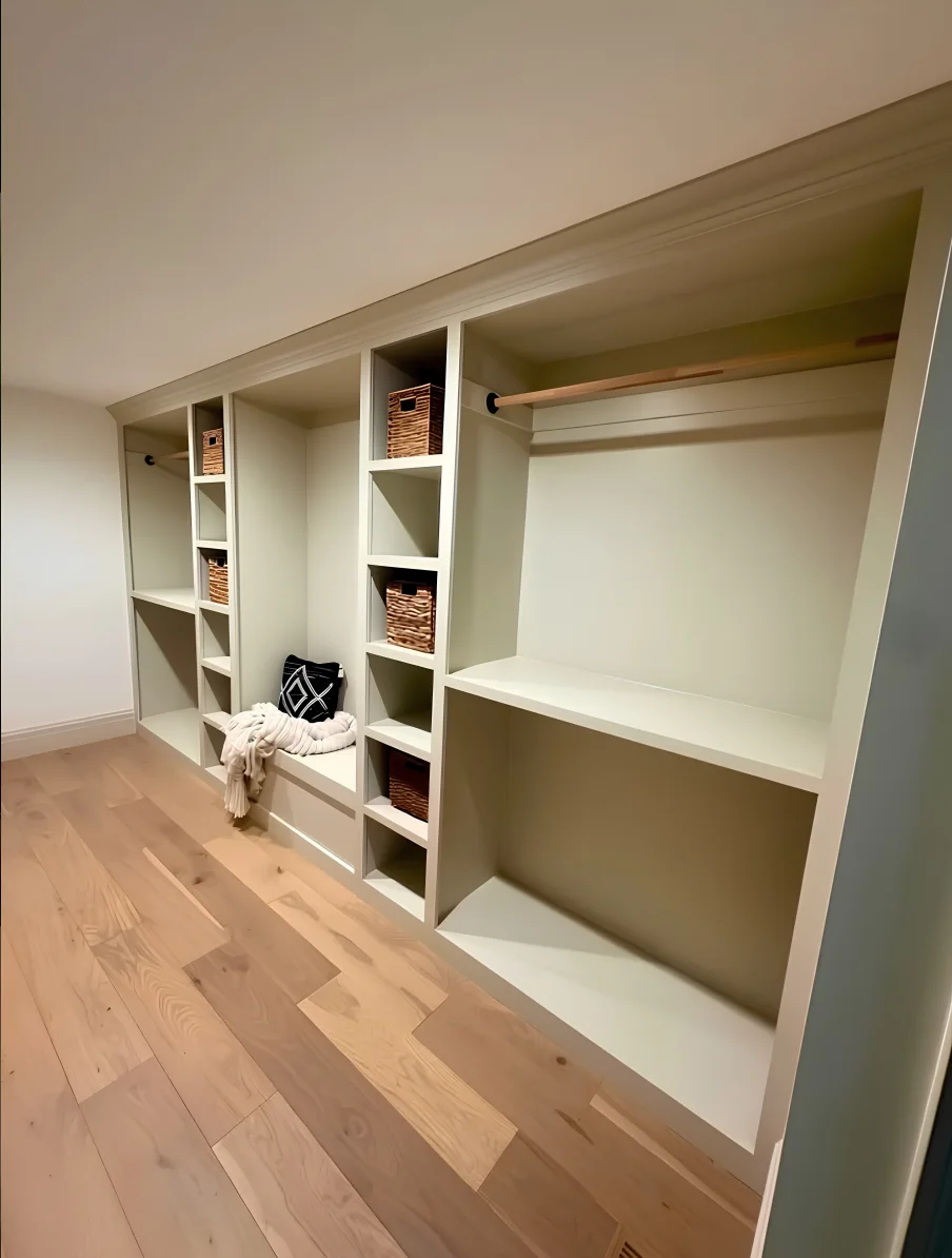 Painted closet built-ins with a bench, open cubbies, shoe shelves, and hanging storage
