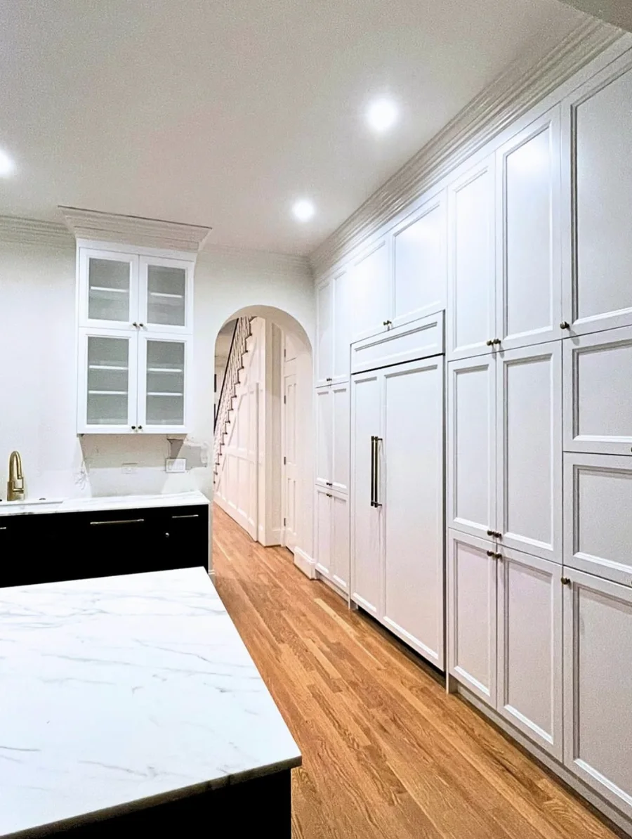 High-end two-tone kitchen with charcoal and white cabinets, veined quartz, and brass hardware